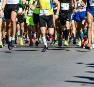 Läkarintyg tävling En grupp löpare i färgglada kläder som deltar i ett lopp på en asfalterad väg.